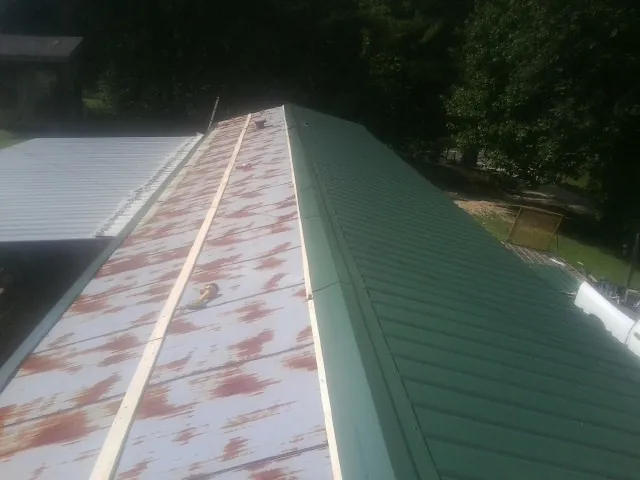 Old rusted panels beside newly installed green metal roofing — Wind Damage Roof Repair by Roofing Brothers in Orangeburg