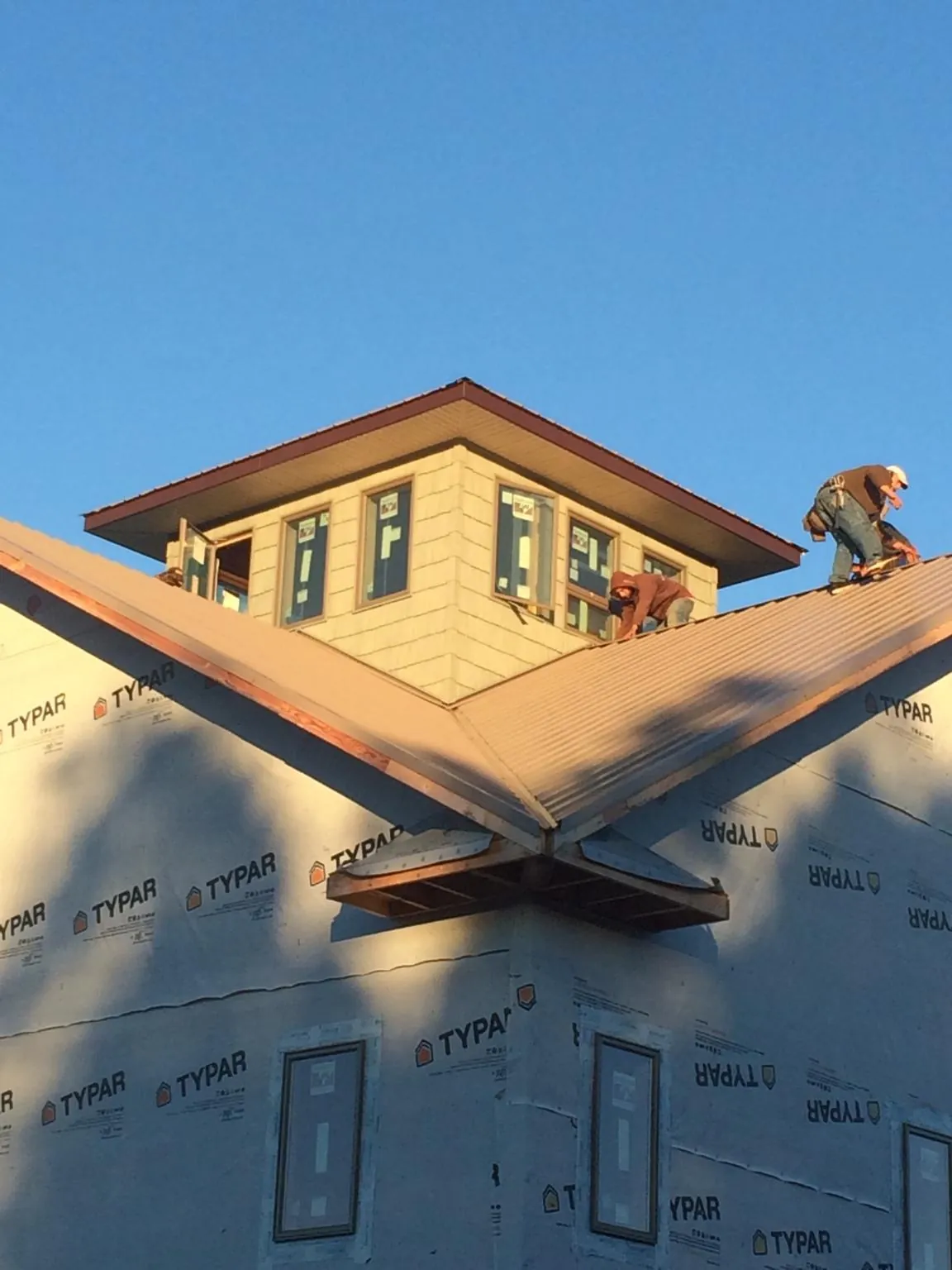 Roofers working around a rooftop cupola on a new metal roof at sunset — Roof Waterproofing in Orangeburg by Roofing Brothers